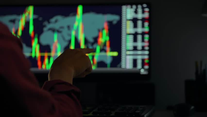 A person analyzes stock market data on a large monitor displaying colorful graphs of financial trends. The setting is dimly lit, focusing on the screen's vibrant colors and patterns - Powered by Shutterstock - Get 15% off with code: PIKWIZARD15