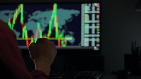 A person observes stock market trends on a computer in a dimly lit room. Colorful graphs and data visualizations display market fluctuations and trading activity, indicating investment strategies - Powered by Shutterstock - Get 15% off with code: PIKWIZARD15