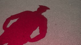 Silhouette of a male cop or police officer stepping in and standing with hands on his waist and looking side to side. View of pavement or road. Policeman checking crime scene, Flashing police lights - Powered by Shutterstock - Get 15% off with code: PIKWIZARD15