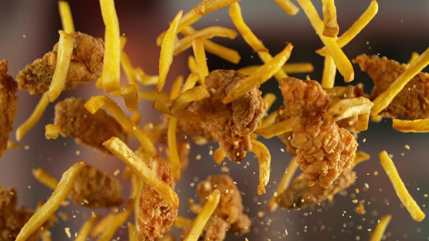 Super slow motion of flying tasty french fries and chicken pieces with camera movement. Filmed on high speed cinema camera, 1000 fps.