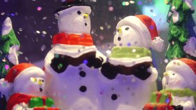Close-up of cheerful snowmen figurines with scarves and hats inside a snow globe, surrounded by glitter and festive decorations - Powered by Shutterstock - Get 15% off with code: PIKWIZARD15