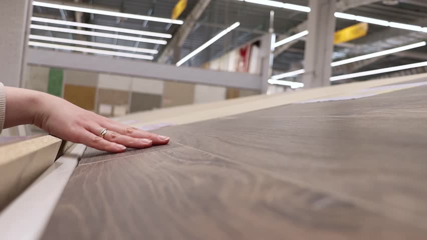 A woman's hand touches tiles in a hardware store. Choosing materials for home renovation.