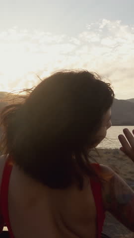 Asian fitness woman in bikini swimwear waving hands and ride cabrio car into sunset meet adventures. Back view Beautiful athletic body. Young Girl Pretty Asian Enjoy Vacation Unsurpassed Landscape at