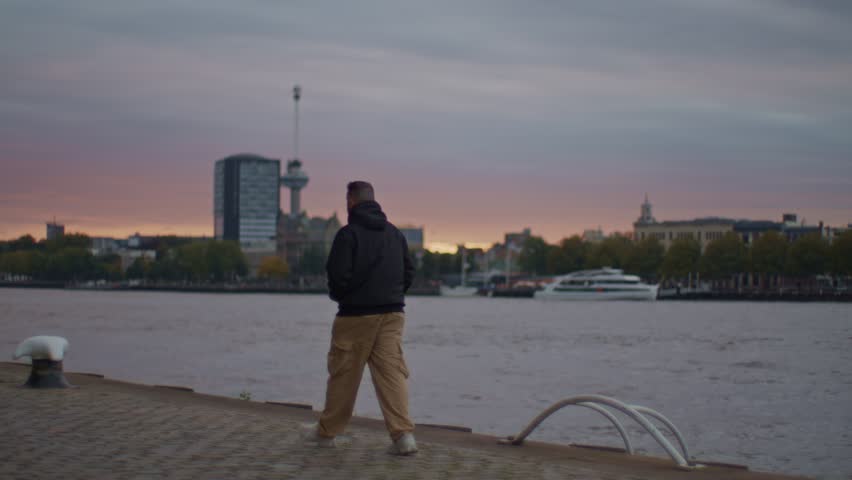 A Greek European male man guy model walks on the streets of Rotterdam with city town evening sunset view