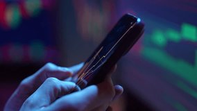 Investor male using smartphone with stock market charts displayed on screen, computer screen with charts on blurred background, creating dark and focused trading atmosphere, close-up , slow motion. - Powered by Shutterstock - Get 15% off with code: PIKWIZARD15