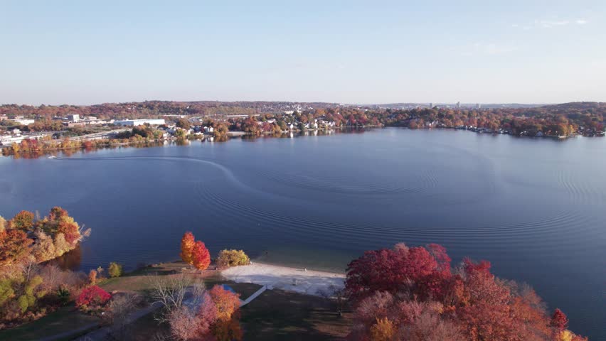 Aerial footage over Indian Lake in Worcester, Massachusetts during the fall foliage peak. Downtown Worcester is visible in the distance.