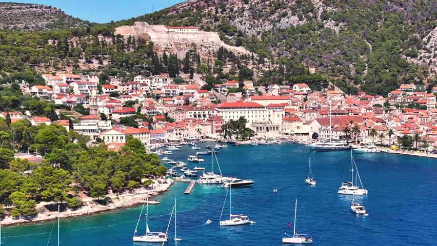 Hvar, Croatia, with this 4K drone shot capturing the vibrant waterfront. Sunlit waves, crystal-clear water, and sail boats. This picturesque island in Croatia
