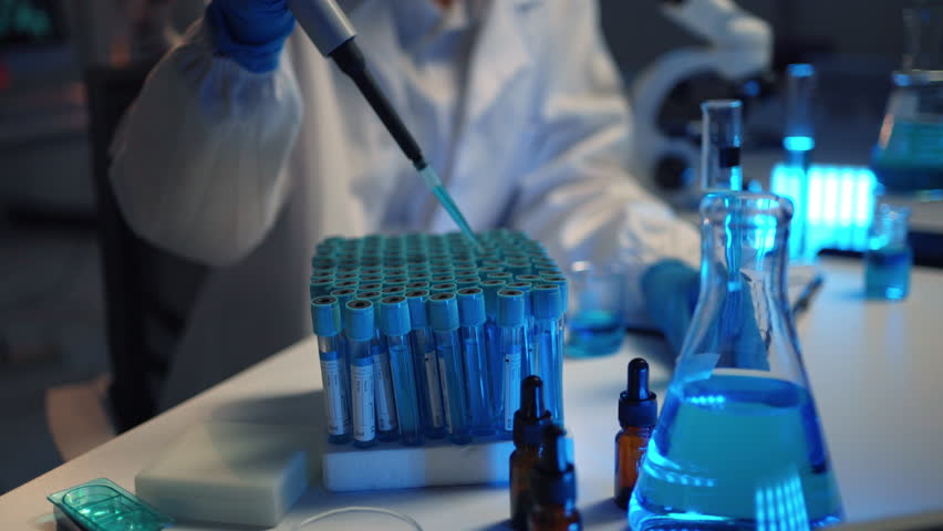 Scientist transferring blue liquid from a test tube using a pipette in a laboratory setting - Powered by Shutterstock - Get 15% off with code: PIKWIZARD15