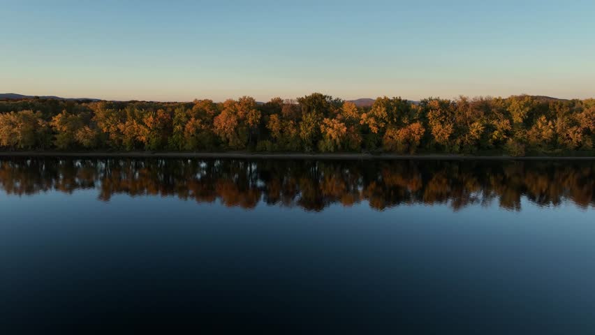 Autumn colors reflect on the calm Connecticut River at sunset near Hadley, Massachusetts