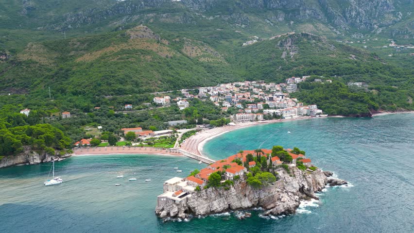 Sveti Stefan Island, aerial perspective. Drone circling arround the island. Famous and luxury travel destination in Montenegro. Boats in the middle of the bay.
