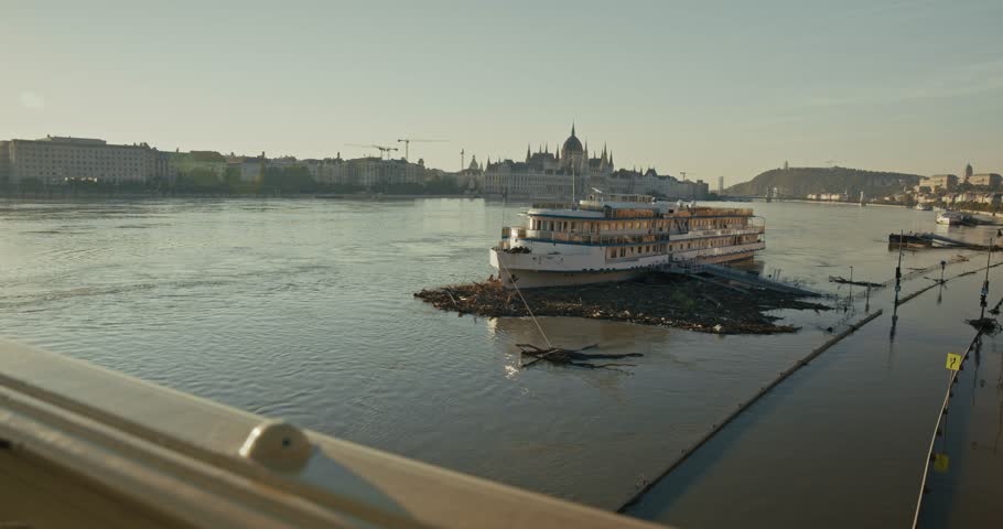 Boat surrounded by debris in flooded river with the Hungarian Parliament in the background, Budapest, Hungary