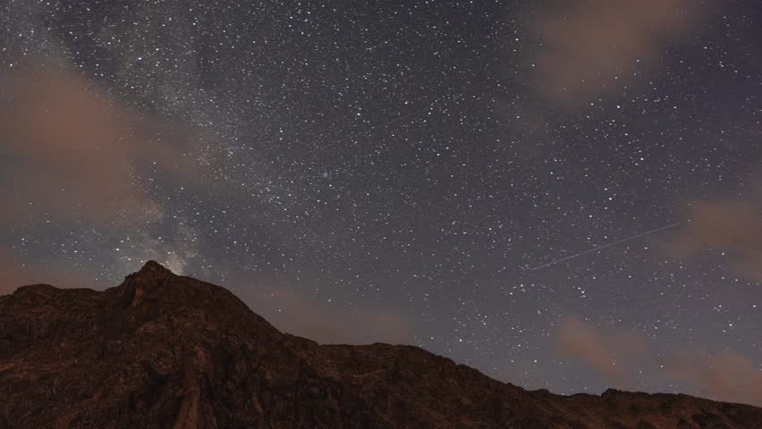 Timelapse of a starry night in the Austrian Alps, featuring the Milky Way stretching across the sky above the majestic mountain landscape, offering a breathtaking view of the universe.