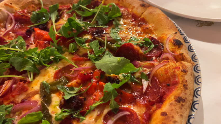 Traditional Italian spicy pepperoni pizza with red onions and rocket salad, perfect crust, real authentic Neapolitan pizza, yummy food, 4K shot