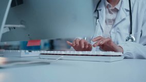 Female doctor typing on a keyboard at her desk in a medical office, managing patient records and healthcare information - Powered by Shutterstock - Get 15% off with code: PIKWIZARD15