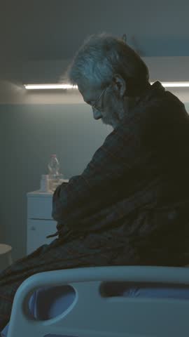 Sad hopeless senior sitting in a hospital bed alone