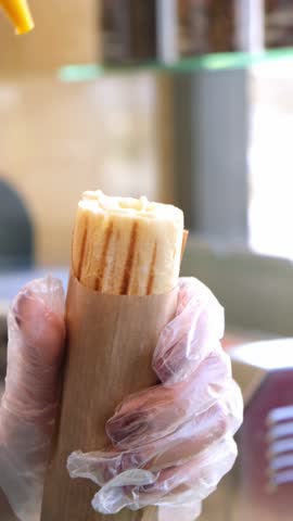 A man makes a French hot dog. the sausage and hot dog bun is baked on the grill. ketchup, mustard and mayonnaise pour into a hot dog bun