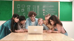 Caucasian teacher and diverse student looking at laptop at classroom. Cute multicultural children learning about coding program or generated program by using software while teacher teaching. Pedagogy. - Powered by Shutterstock - Get 15% off with code: PIKWIZARD15