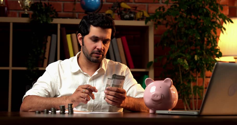 Indian Asian bearded young man focused on counting Indian currency notes while managing personal finances, preparing a detailed checklist for monthly budgeting and expenses