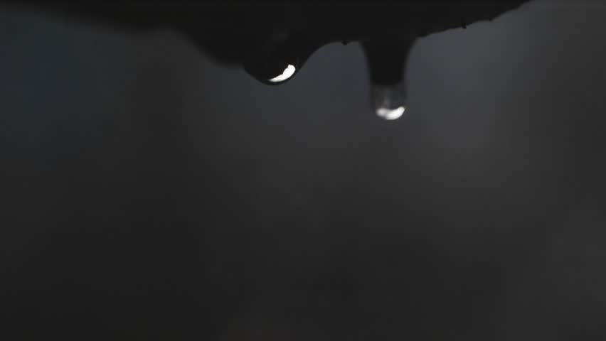 Slow-motion water droplets fall from rocky cliffs, each drop visible. In the background, a gentle waterfall flows, symbolizing water purity and scarcity.