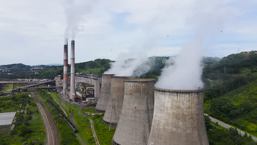 View from above. The camera flies over a thermal power plant. Smoking cooling towers of the thermal power plant.