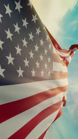 Wavy flag of United States of America blowing in the wind in slow motion. Waving official USA flag team symbol abstract vertical background. Blue sky with clouds. World countries flying flags concept