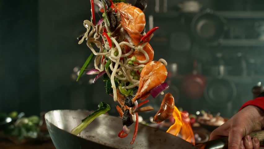 Super Slow Motion of Flying Asian Meal with Vegetable and Prawns into Wok Pan. Filmed on High Speed Cinema Camera, 1000 fps