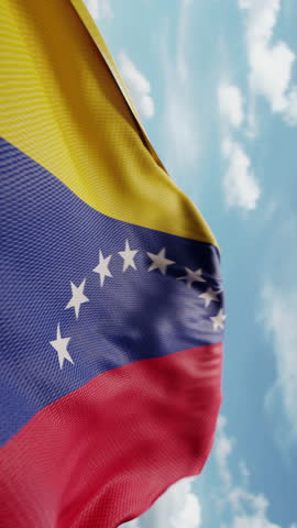 Wavy flag of Venezuela blowing in the wind in slow motion. Waving official Venezuelan flag team symbol abstract vertical background. Blue sky with clouds. World countries flying flags concept