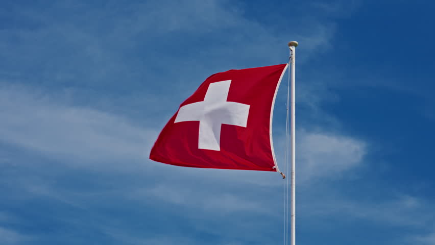 Swiss flag against a blue clear sky in a summer day in Switzerland