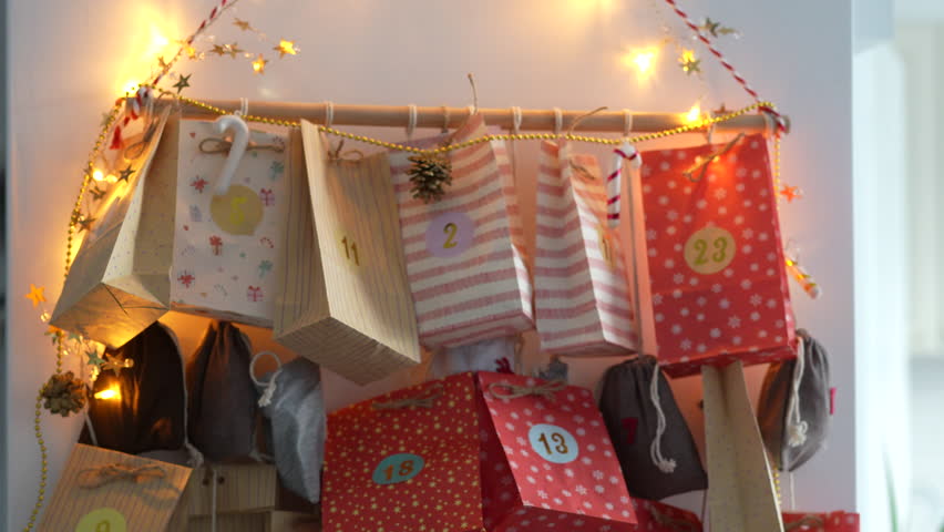 The snow globe, held in the palm, in front of the Christmas advent calendar. Colored bags and lights can be seen in the blurry background