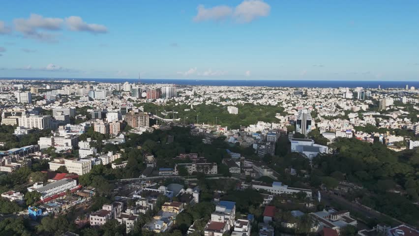 An aerial video of Chennai in the morning would offer a breathtaking view of the city awakening. The sun would cast a golden glow over the city. Clouds and Buildings blue sky Gemini bridge