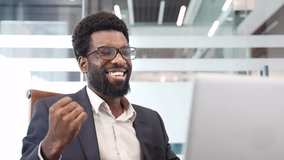 Happy handsome african american businessman in formal suit receiving good news on laptop sitting at desk in business office. Satisfied bearded entrepreneur expressing happiness and success. Close up - Powered by Shutterstock - Get 15% off with code: PIKWIZARD15