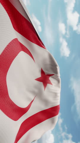 Wavy flag of Northern Cyprus blowing in the wind in slow motion. Waving official North Cypriot flag team symbol abstract vertical background. Blue sky with clouds. World countries flying flags concept