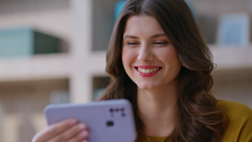 Freelancer watching video at cellphone sitting remote workplace closeup. Positive woman smiling enjoying social media content at smartphone. Relaxed businesswoman holding horizontal mobile phone.