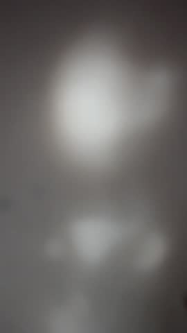 Real light leaks, raw footage with noise, grain, blur, bokeh effect. Abstract overlay vertical background video. Sunbeams on white wall