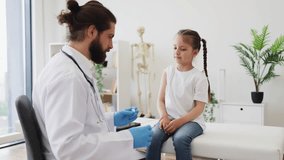 Doctor carefully administers vaccine to young Caucasian girl sitting on medical couch. Child appears calm and composed. Scene conveys healthcare, safety, and trust in medical environment. - Powered by Shutterstock - Get 15% off with code: PIKWIZARD15