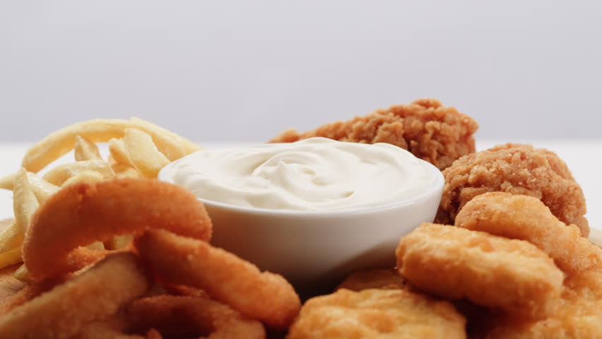Curry cheese lemon sauce close up, fast food cafe Pouring fries potato and fry chicken in mayo yellow creamy cheese sauce close-up. Eat chicken nuggets with Peruvian sauce. Fast and junk food concept.