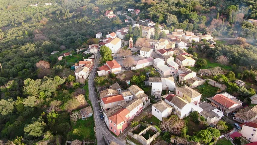Greece, mountain village Agioi douloi aerial panoramic view, Corfu. Traditional tile roof , forest trees, cloudy sunset sky, Autumn