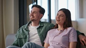 Laughing couple looking film on TV at cozy apartment sofa closeup. Two viewers having fun spending time at home with television. Overjoyed pair enjoy amusing entertainment program on comfortable couch - Powered by Shutterstock - Get 15% off with code: PIKWIZARD15