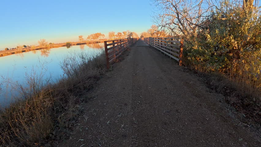 First person POV from riding a mountain bike on a long trestle across a lake, fall scenery in northern Colorado, Great Western Bike Trail