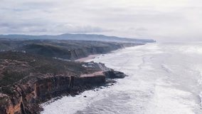 A stunning Aerial view of a rocky Hawaiian coastline with towering cliffs meeting the vast ocean. Waves crash against the shore, while greenery and scattered buildings line the cliffs. - Powered by Shutterstock - Get 15% off with code: PIKWIZARD15