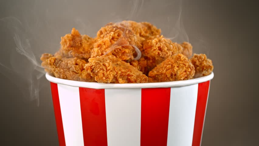 Slow Motion Shot of Fried Chicken Pieces and Smoke Rotating in a Bucket on Grey Background.