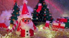 A close-up view of handmade Christmas festival decorations featuring Santa Claus, snowman, gift boxes, tree and yellow light, festive ambiance with Snow fall and holiday spirit - Powered by Shutterstock - Get 15% off with code: PIKWIZARD15