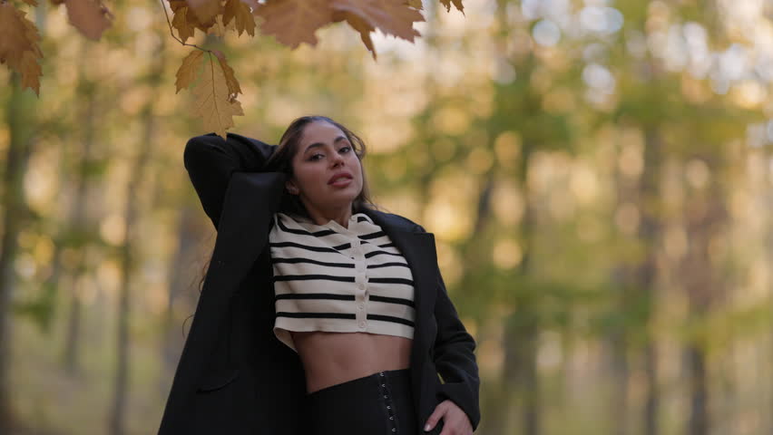 A beautiful woman with long hair enjoys nature in the forest during autumn.