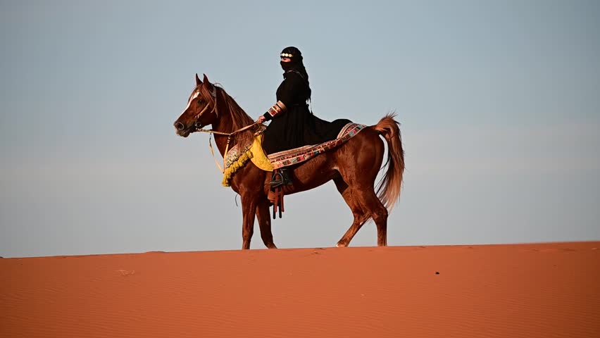 A Saudi woman, dressed in traditional attire, rides gracefully on a horse through the vast desert of Saudi Arabia. The golden sands stretch endlessly, with her figure embodying strength and culture
