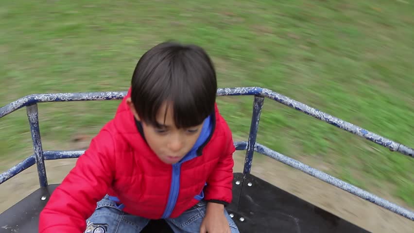 Joyful moments unfold as a young boy spins around on a merry-go-round
