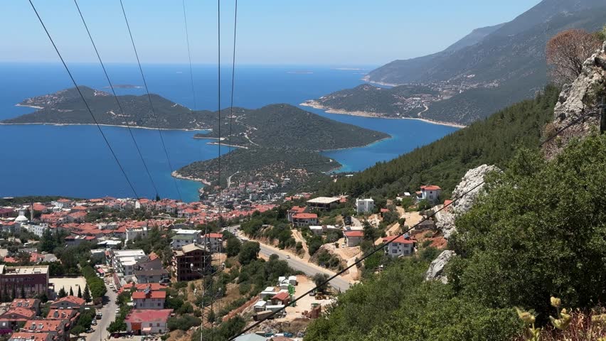 An aerial view of Kas town surrounded by the lush hills and blue sea with peninsula and islands, on a sunny day in Turkey