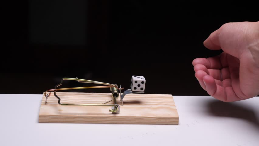 Hand reaching towards mouse trap with dice