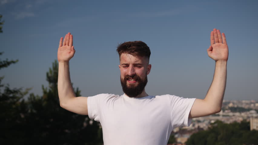 Yoga stability, Young man, Yoga self-care. With stunning cityscape as backdrop, young man engages in yoga on purple mat atop hill, emphasizing mindfulness and balance.