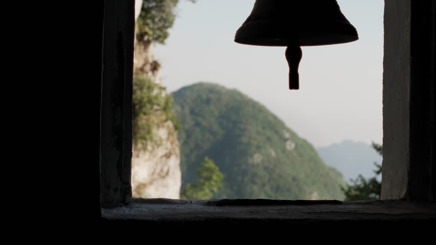 A church bell sits above the mountain cliffs of Campania in Italy.