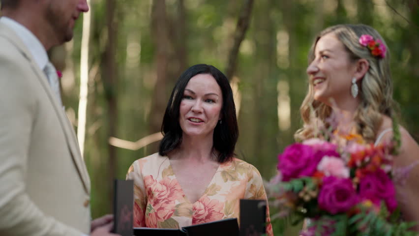 Close Up Brunette Wedding Officiant Smiling During Ceremony With Caucasian Couple In Outdoor Setting, 4K Resolution Slow Motion